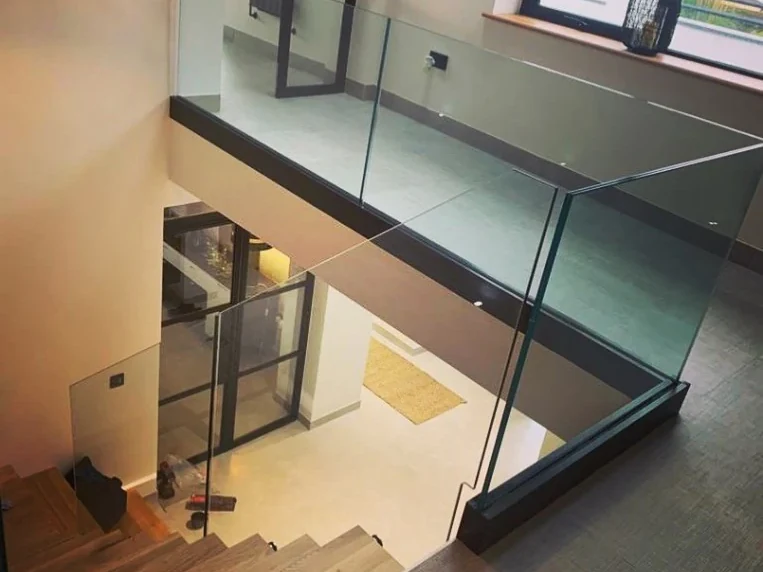 Frameless glass staircase balustrade in a dark contemporary interior in Swansea by Swansea Glass Balustrades